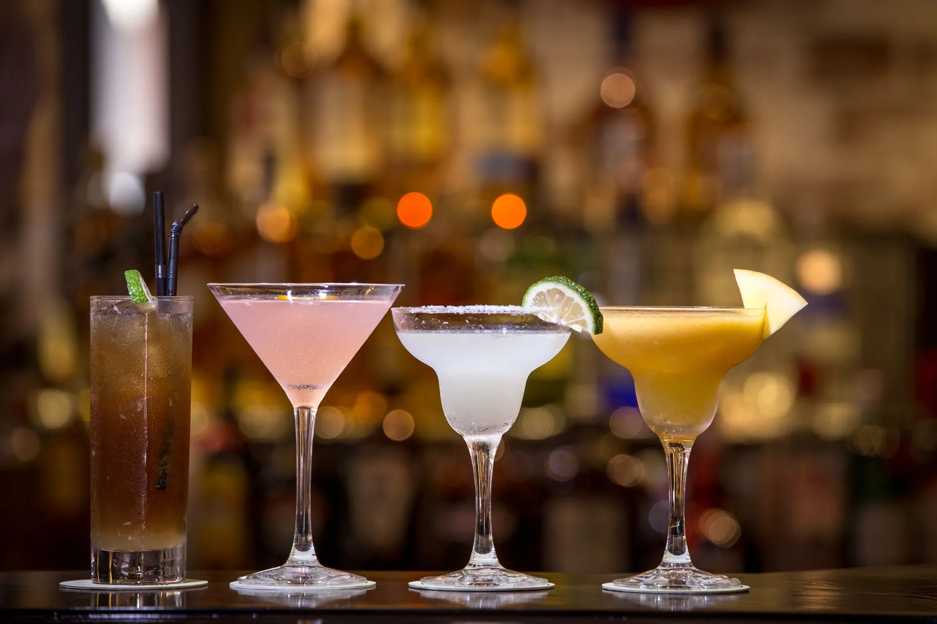 Carta de cócteles servida en la barra de un bar con varias copas