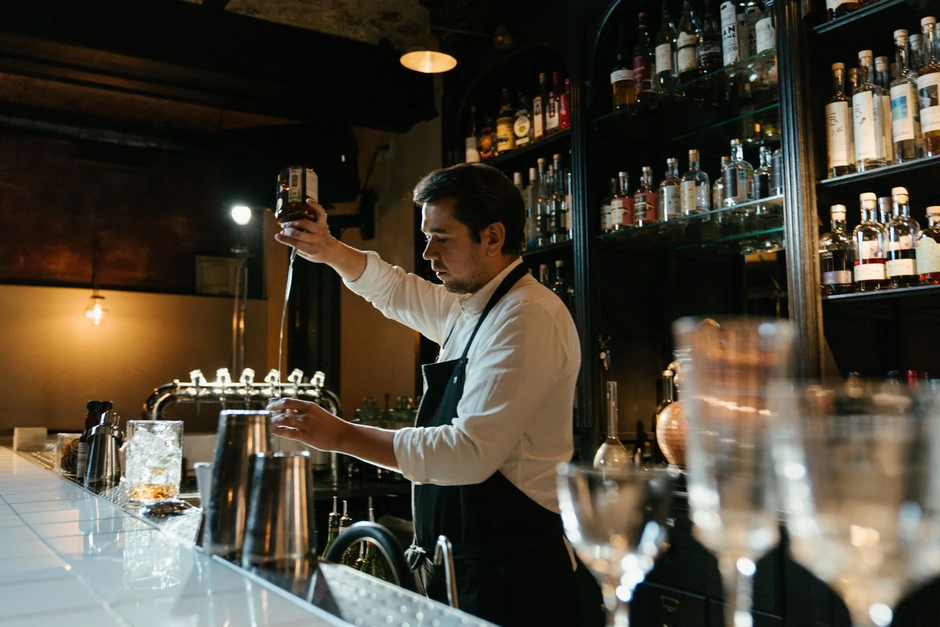 Barra de bar con ambiente nocturno y bartender sirviendo